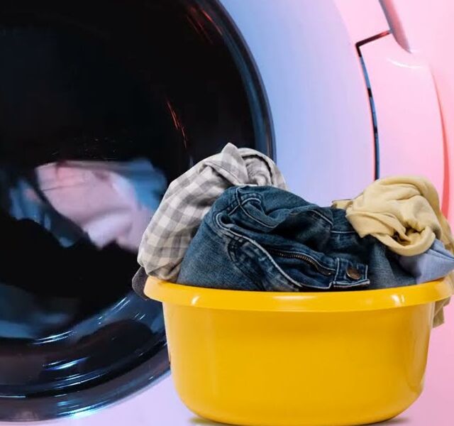A basin of clothes in front of a washing machine at work