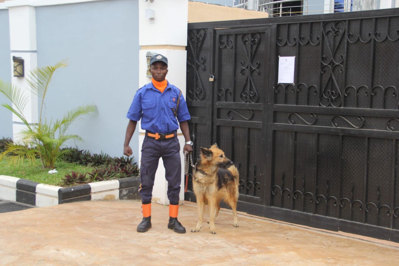 A Lashone Security guard with a guard dog at an estate gate